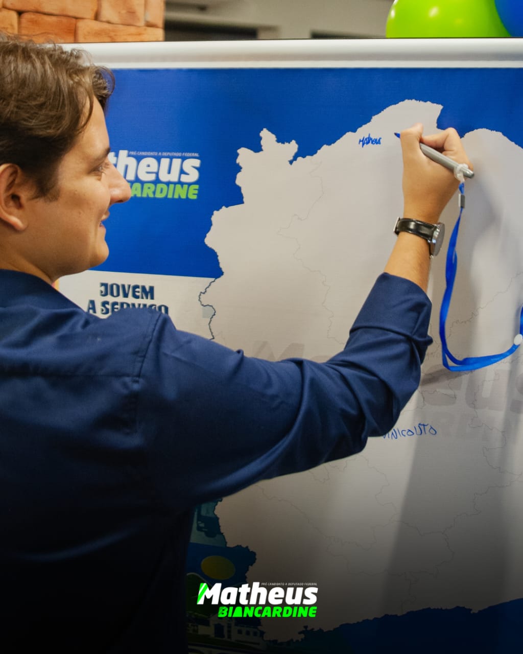 Matheus Biancardine assinando o mapa de Minas Gerais em um painel da campanha